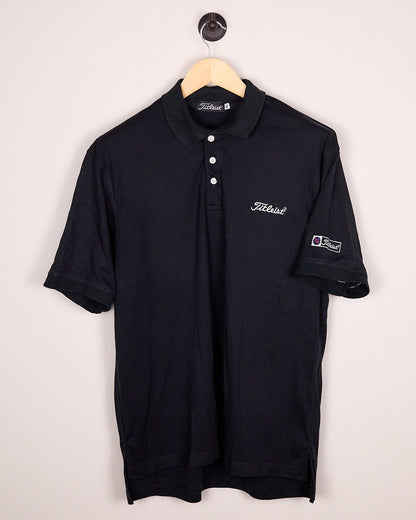 Black polo shirt on a hanger against a light gray background